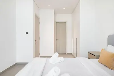 a bedroom with a white bed with towels on it at Restay Homes - Fancy 2BR in Belgravia Heights - Pool access in Dubai