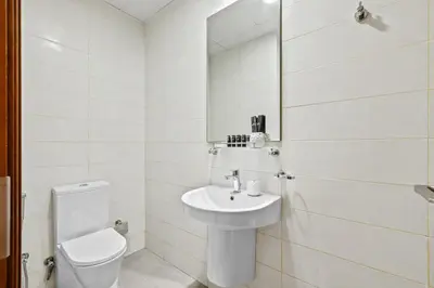 a white bathroom with a toilet and a sink at Luxury 1 BR - Walk to Dubai Mall & Burj Khalifa in Dubai