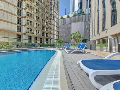 a swimming pool with lounge chairs and a building at Luxury 1 BR - Walk to Dubai Mall & Burj Khalifa in Dubai