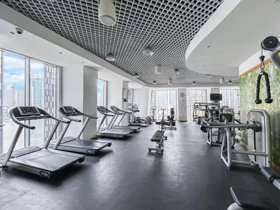 a gym with a row of treadmills and machines at 44th Floor Home at Cayan Tower with Panoramic Views in Dubai