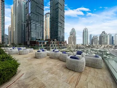 a rooftop patio with chairs and a view of a city at 44th Floor Home at Cayan Tower with Panoramic Views in Dubai