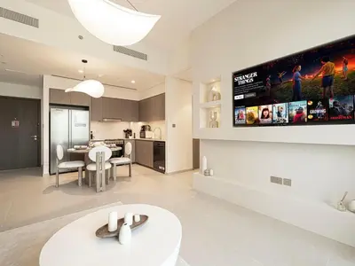 a kitchen and living room with a tv on the wall at Grande Signature Residences by Prestige Nest in Dubai