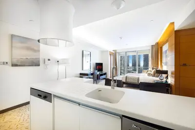 a white kitchen with a sink and a bedroom at Burj Khalifa View & Mall Entry in 3 Mins & Sleeps 3 Adults in Dubai