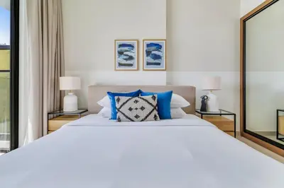 a bedroom with a large white bed with blue pillows at GuestReady - Jumeirah Village haven with pool view in Dubai
