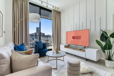 a living room with a couch and a tv at GuestReady - Jumeirah Village haven with pool view in Dubai