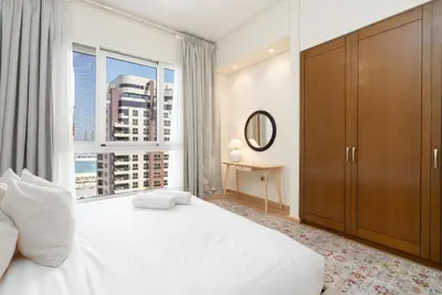 a bedroom with a large white bed and a window at Marina Residence 6 - Luxurious Two Bedroom and Maid's - Lake and Sea View in Dubai