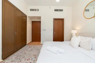 a bedroom with a white bed and wooden cabinets at Marina Residence 6 - Luxurious Two Bedroom and Maid's - Lake and Sea View in Dubai
