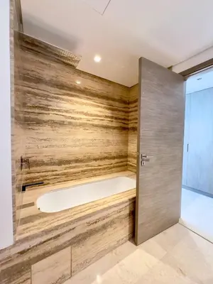 a bathtub in a bathroom with a wooden wall at Unique Luxury White 2BR Apartment in Dubai