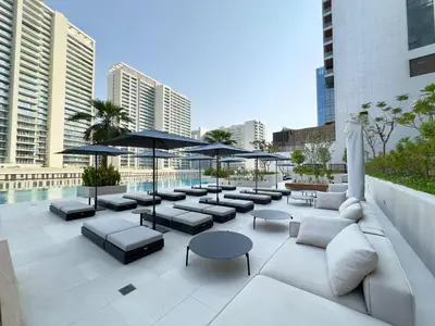 a rooftop patio with couches and tables and umbrellas at Contemporary Urban 2BR Apartment in Dubai