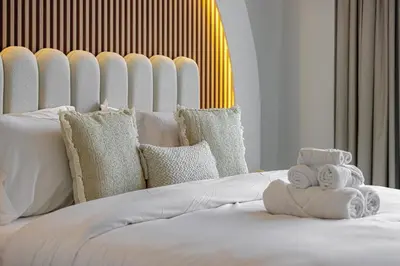 a white bed with pillows and towels on it at 2BR Burj & Fountain View 5 mins to Dubai Mall in Dubai