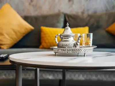 a silver tea pot on a table in front of a couch at Spectacular Burj View from Infinity Pool in Dubai