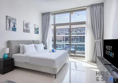 a bedroom with a bed and a large window at Bright Studio in Loreto DAMAC Hills - Pet-Friendly in Dubai
