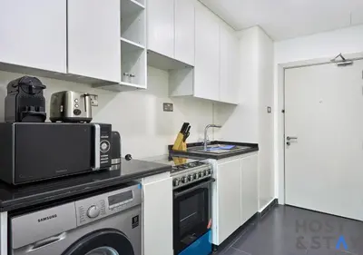 a kitchen with white cabinets and a stove top oven at Bright Studio in Loreto DAMAC Hills - Pet-Friendly in Dubai