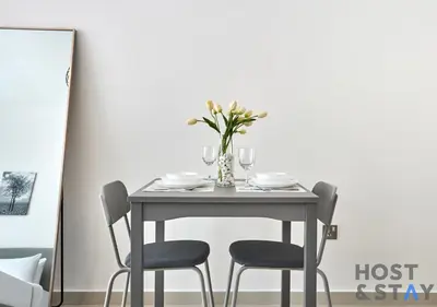 a table with two chairs and a vase with flowers at Bright Studio in Loreto DAMAC Hills - Pet-Friendly in Dubai