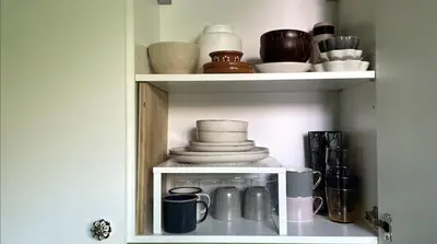 a shelf with dishes and other items in a cabinet at Palm Oasis Guest House in Dubai