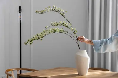 a person is holding a vase with flowers on a table at Waterfront View, Boutique apartment, Lagoon Access in Dubai