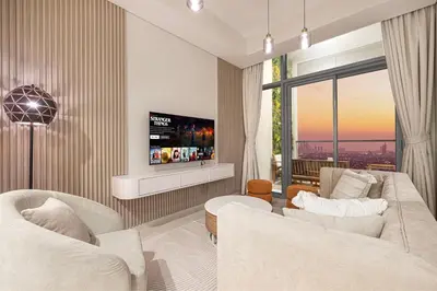 a living room with two white couches and a tv at Cozy Sunset Retreat - Burj, Palm & Sea View - 2 BR in Dubai