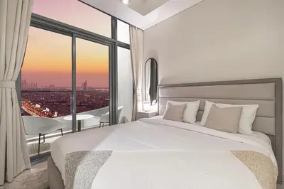 a bedroom with a white bed and a large window at Cozy Sunset Retreat - Burj, Palm & Sea View - 2 BR in Dubai