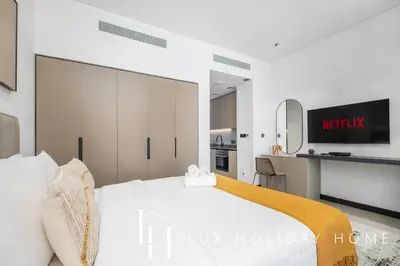 a bedroom with a white bed and a tv at LUX The Northside Studio in Dubai