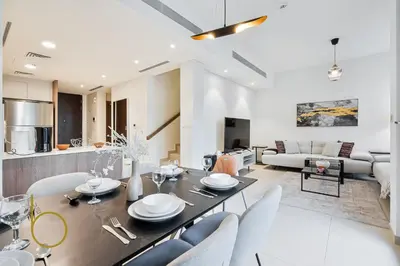 a dining room and living room with a table and chairs at Bookable - 4 Bedroom Elan 1 Tilal Al Ghaf Villa in Dubai