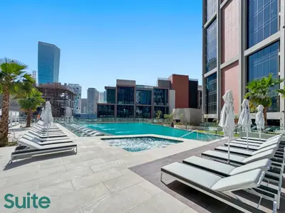 a swimming pool with lounge chairs and a building at Lavish 1-Bedroom with Burj Khalifa view in Peninsula in Dubai