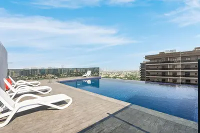 a swimming pool with lounge chairs on a building at Modern Home in Sports City with Rooftop Pool in Dubai