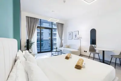 a white bedroom with a white bed and a living room at Modern Home in Sports City with Rooftop Pool in Dubai