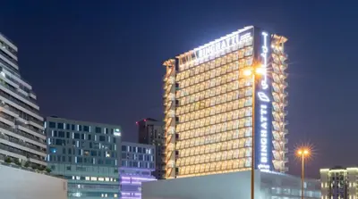 a tall building with lights on it at night at Pool View 1BR with Spacious Balcony, Short Drive to Downtown, Binghatti Gateway, Al Jaddaf by Deluxe Holiday Homes in Dubai