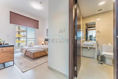 a bedroom with a bed and a bathroom at Pool View 1BR with Spacious Balcony, Short Drive to Downtown, Binghatti Gateway, Al Jaddaf by Deluxe Holiday Homes in Dubai