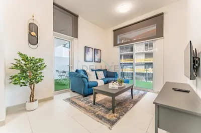 a living room with a blue couch and a table at Pool View 1BR with Spacious Balcony, Short Drive to Downtown, Binghatti Gateway, Al Jaddaf by Deluxe Holiday Homes in Dubai