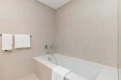 a white bathroom with a tub and towels at Luxury 2BR and Study Water View in Al Wasl in Dubai