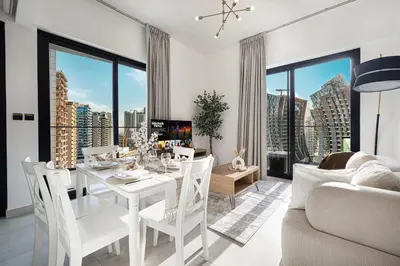 a living room with a white dining room table and chairs at Luxury 2BR with Canal View Burj Khalifa view and Infinity Pool Access in Dubai