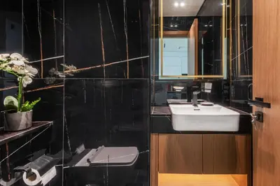 a black tiled bathroom with a sink and a mirror at GuestReady - Stunning unit at Binghatti House in Dubai