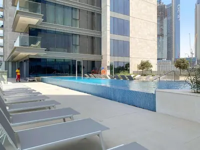 a building with a swimming pool in front of a building at Silkhaus Charming 1BDR in Canal Front Tower in Dubai