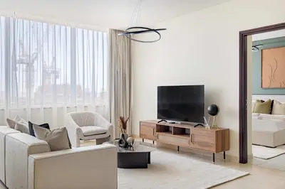 a white living room with a tv and a couch at Silkhaus Cityscape 1BR in Sky Gardens with Metro access in Dubai
