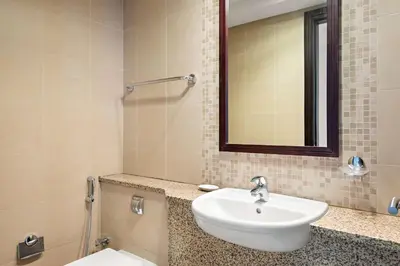 a bathroom with a sink and a mirror and a toilet at Silkhaus Urban 1BDR Escape in Heart of DIFC in Dubai
