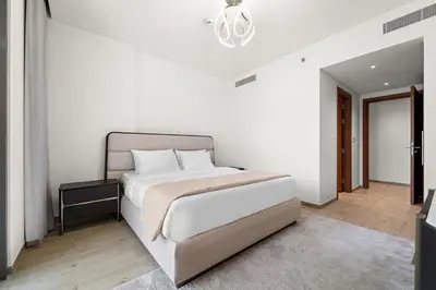 a white bedroom with a large bed and a chandelier at 3BR Central Park, Prime Dubai Location in Dubai
