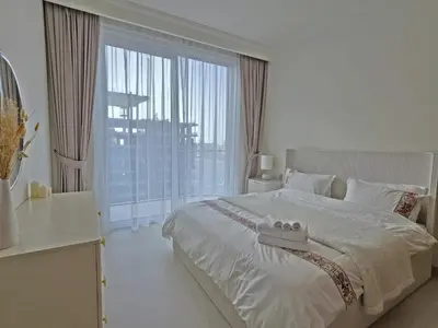 a white bedroom with a bed and a large window at Brand New 1BR , Fully Furnished in Dubai