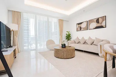 a white living room with a couch and a tv at Escape24 Luxury 1BR with Sea View and Beach Access, Dubai Harbour in Dubai