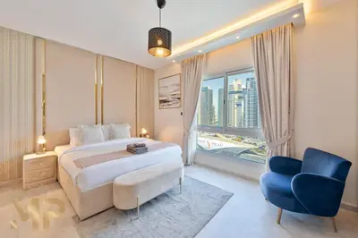 a bedroom with a large bed and a blue chair at Marcopolo -Enjoy Marina views from a cozy 1BR in Dubai Marina in Dubai