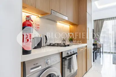 a kitchen with a stove and a washing machine at Bloomfields Deluxe Studio In Azizi Riviera in Dubai