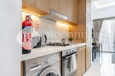 a kitchen with a stove and a washer and dryer at Bloomfields Deluxe Studio In Azizi Riviera in Dubai