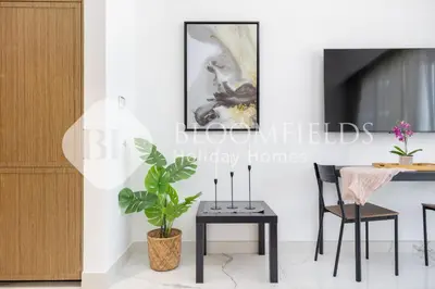 a dining room with a table and a plant at Bloomfields Deluxe Studio In Azizi Riviera in Dubai