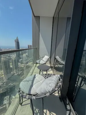 a balcony with two chairs and a bed on a building at Nasma Luxury Stays - Chic HighRise 1 BR in the Heart of Dubai in Dubai