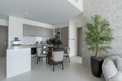 a kitchen and living room with a table and chairs and a plant at Nasma Luxury Stays - Chic HighRise 1 BR in the Heart of Dubai in Dubai