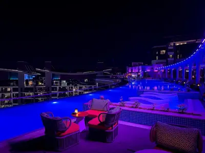 a swimming pool with chairs and tables at night at Seven Palm Residence with stunning view in Dubai