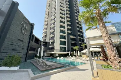a swimming pool with chairs and a tall building at Ahad Residences Skyline Studio in Business Bay in Dubai