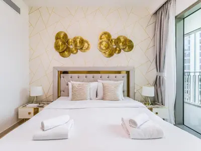 a bedroom with a large white bed with gold decorations at TRPS - Downtown Views II Tower 2, Downtown Dubai - 3BR plus Maids - Burj Khalifa View - Walk to Dubai Mall in Dubai