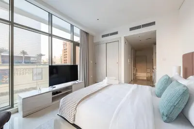 a bedroom with a large white bed and a large window at Elegant Beachside Studio in Prime Palm Location in Dubai