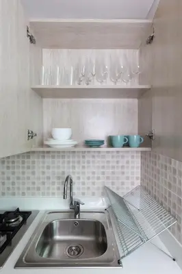 a kitchen with a sink and glasses on shelves at Elegant Beachside Studio in Prime Palm Location in Dubai